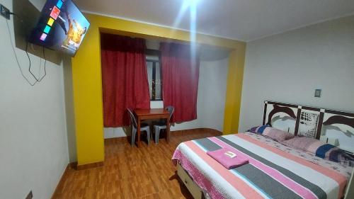 een slaapkamer met een bed en een televisie en een tafel bij SOL DEL NORTE in Ayacucho