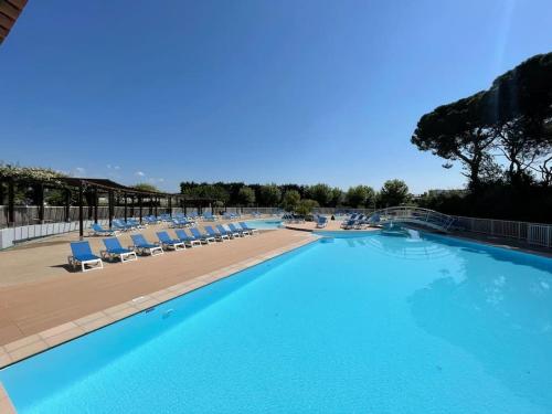 une grande piscine avec des chaises longues et une plage dans l'établissement Petit lac appartement Mandelieu-la-Napoule, à Mandelieu-la-Napoule