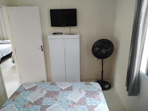 1 dormitorio con 1 cama y TV en la pared en Acomodações Casa 1 en Cananéia