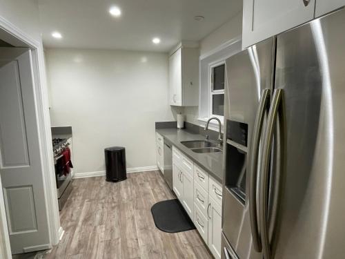 a kitchen with white cabinets and a stainless steel refrigerator at Sunset Dream Cottage in Los Angeles