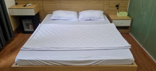 un letto con lenzuola e cuscini bianchi in una stanza di Khôi Đại Hotel a Buôn Ma Thuột