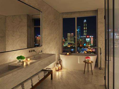 a bathroom with a view of a city at night at The Shanghai EDITION in Shanghai