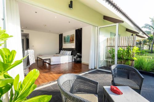 ein Schlafzimmer mit einem Bett und Stühlen in einem Zimmer in der Unterkunft TUI BLUE Nam Hoi An Resort in Tam Kỳ