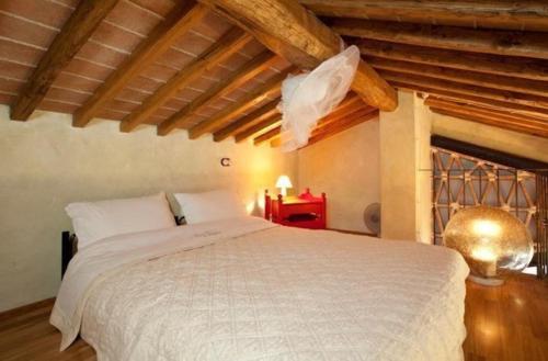 sypialnia z białym łóżkiem w pokoju z drewnianym sufitem w obiekcie Nettes Appartement in Mignana mit gemeinsamem Pool und Panoramablick w mieście Vinci