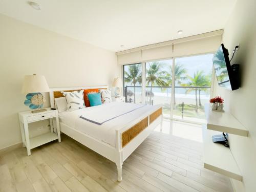 a white bedroom with a bed and a large window at Olas del Mar by Playa Caracol Residences in Punta Chame