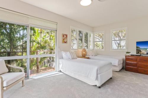 a bedroom with two beds and a tv and windows at A Tropical Family Oasis in Sunshine Beach in Sunshine Beach