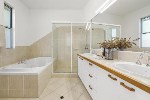 a bathroom with two sinks and a tub and a shower at A Tropical Family Oasis in Sunshine Beach in Sunshine Beach