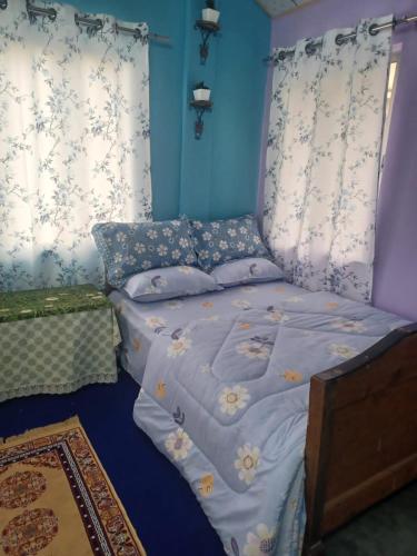 a bedroom with a bed with blue walls at MOKTAN HOME STAY 1 in Kalimpong