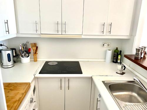 a white kitchen with a stove and a sink at Bossa Collection Suites in Playa d'en Bossa