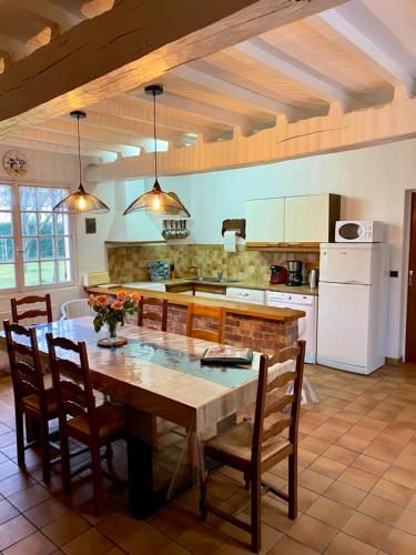 une cuisine avec une grande table et des chaises en bois dans l'établissement Maison charmante à Tours-en-Vimeu avec grand jardin clos, à Tours-en-Vimeu