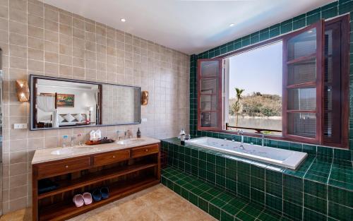 a bathroom with two sinks and a tub and a window at Relaxful Hotel泊岸酒店 in Luang Prabang