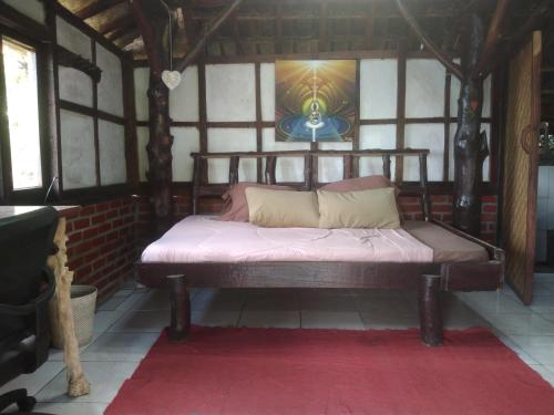 Cama de madera en habitación con alfombra roja en Bali Gems Cabin, en Tabanan
