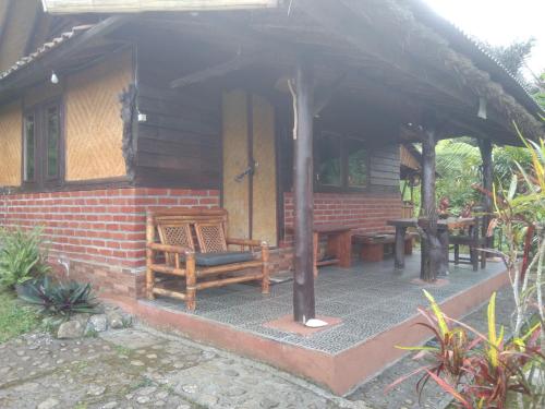Casa con porche con silla y mesa en Bali Gems Cabin, en Tabanan