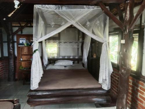 ein Schlafzimmer mit einem Himmelbett in einem Haus in der Unterkunft Bali Gems Cabin in Tabanan