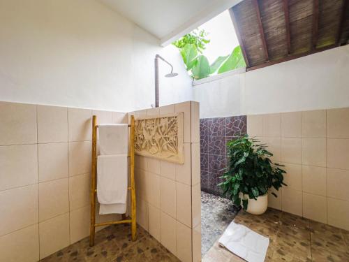 a bathroom with a toilet with a window and a plant at Ubud Shanti Rice Field House By Supala in Ubud