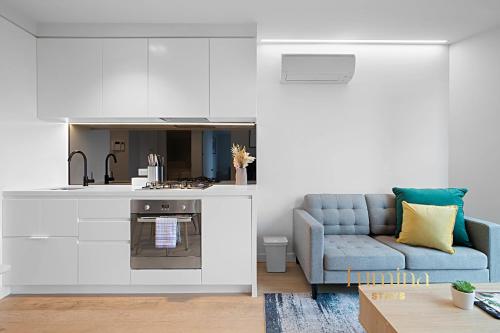 a living room with a blue couch and a kitchen at Lumina Stays - Lighthouse in Melbourne