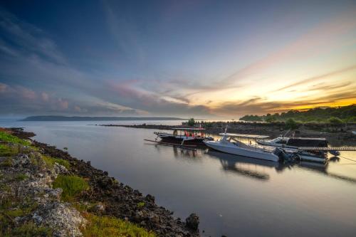 a group of boats docked in a river at sunset at Samawa Seaside Resort in Sumbawa Besar