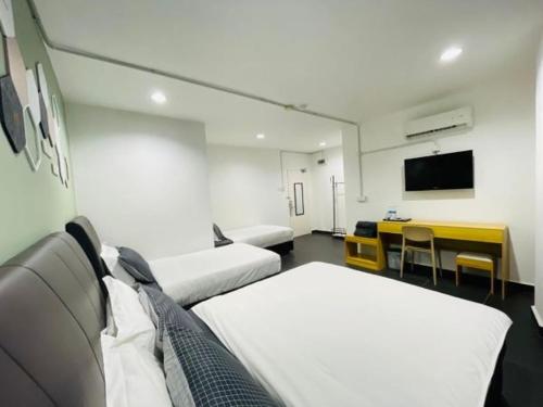 a room with two beds and a table and a television at Halo Rooms Hotel in Wakaf Baharu