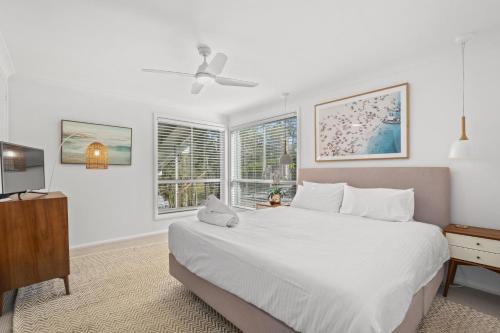 a bedroom with a large white bed and a television at Scenic 4-Bed Lake House 5-min Walk to Avoca Beach in Avoca Beach