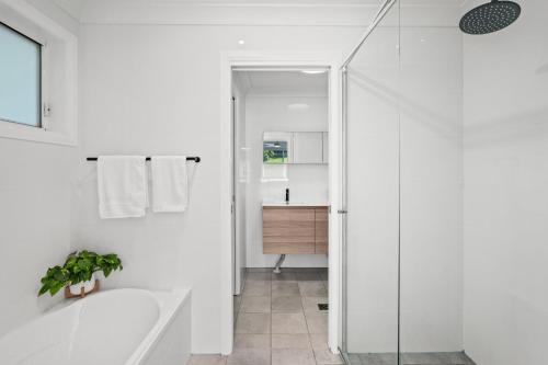 a white bathroom with a tub and a sink at Scenic 4-Bed Lake House 5-min Walk to Avoca Beach in Avoca Beach