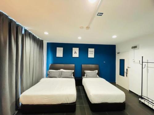 2 łóżka w pokoju z niebieską ścianą w obiekcie Halo Rooms Hotel w mieście Wakaf Baharu