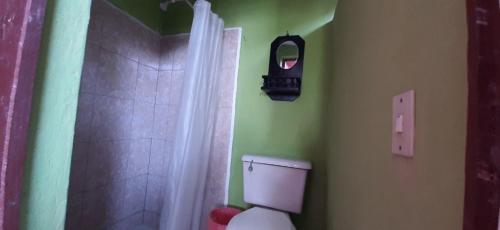 uma casa de banho com um WC e um chuveiro com um relógio. em Casa Zoila Hospedaje em Flores