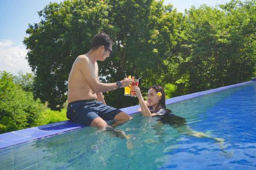 a man and a woman sitting in a swimming pool at Samawa Seaside Resort in Sumbawa Besar