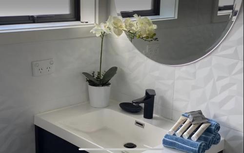 a bathroom sink with a vase of flowers and a mirror at New Lynn Dream guest house in Auckland