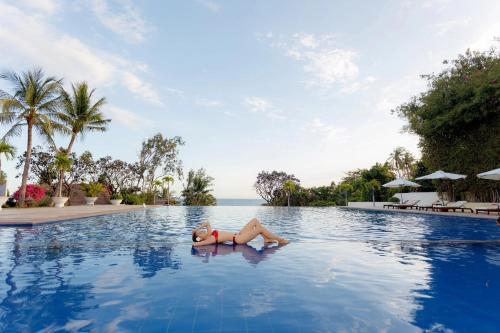 a woman laying in a swimming pool at a resort at Victoria Phan Thiet Beach Resort & Spa in Mui Ne