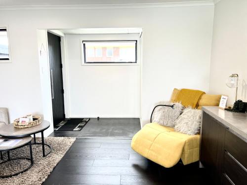 a living room with a yellow couch and a table at New Lynn Dream guest house in Auckland