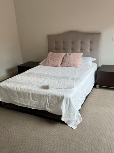 een slaapkamer met een groot bed met witte lakens en roze kussens bij Bentleighs Magnificent Beautifully renovated and extended 1920s period family home. in Melbourne