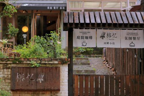 un bâtiment avec des panneaux et une clôture dans l'établissement Ron Inn Xingping Hepan Xiaozhu, à Yangshuo