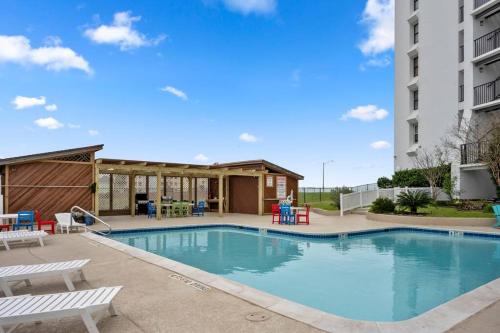 a swimming pool with chairs and a building at Bello condominio con vista al mar, jacuzzi interno in Galveston