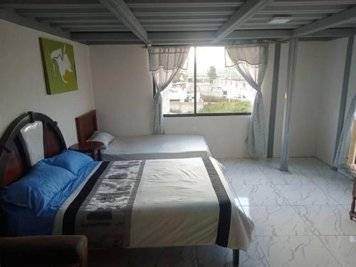 1 dormitorio con 2 camas y ventana en Terraza en las Nubes, en Ibarra