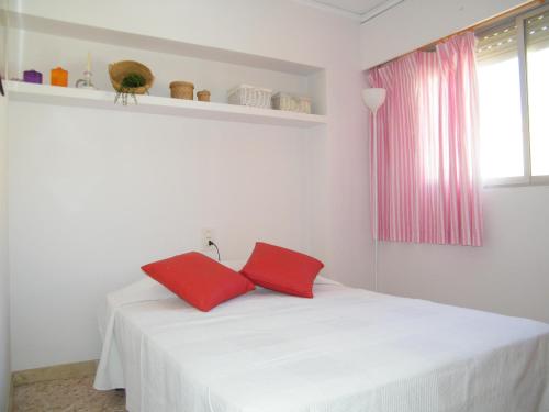 Una cama blanca con dos almohadas rojas. en Apartamento Playa de Gandía, 3 dormitorios, 7 personas - ES-314-8, en Gandía