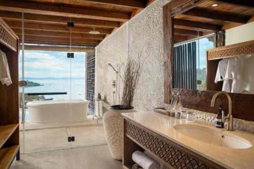 a bathroom with a large tub and a sink at Kalandara Resort Lombok in Senggigi