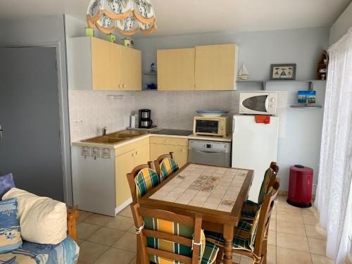 Il comprend une cuisine équipée d'une table et d'un réfrigérateur. dans l'établissement Appartement proche plage, 2 chambres, balcon, garage - FR-1-482-138, à Fort-Mahon-Plage