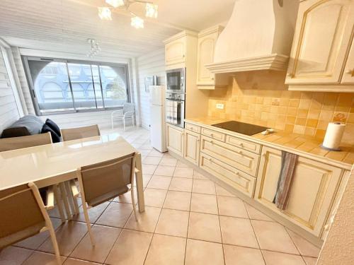 eine Küche mit weißen Schränken sowie einem Tisch und Stühlen in der Unterkunft Appartement Le Grau-du-Roi, 3 pièces, 4 personnes - FR-1-716-66 in Le Grau-du-Roi