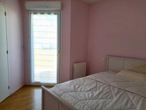 une chambre avec un lit blanc et une grande fenêtre dans l'établissement Appartement charmant près de la plage avec garage et terrasse - Idéal pour famille et amis - FR-1-392-233, à La Turballe