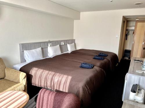 a hotel room with a large bed and a chair at Sunwest Hotel Sasebo in Sasebo