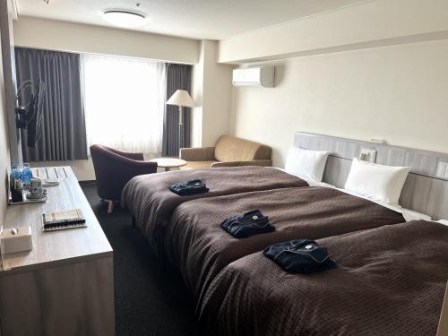 a hotel room with a large bed with black clothes on it at Sunwest Hotel Sasebo in Sasebo