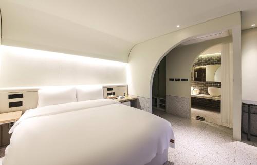 a bedroom with a large white bed and a bathroom at MUTE HOTEL in Busan