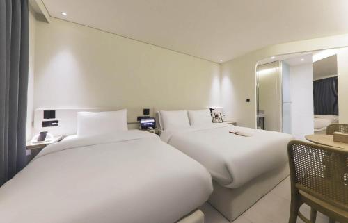 a hotel room with two beds and a mirror at 뮤트호텔 대연 MUTE HOTEL Daeyeon Busan in Busan