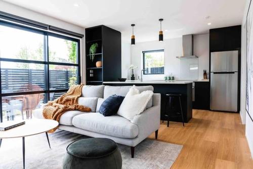 a living room with a couch and a kitchen at New State Of The Art Sunny Warm free Park in Christchurch