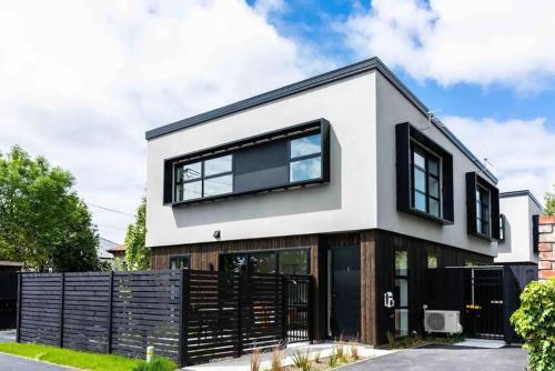 a white house with black windows and a fence at New State Of The Art Sunny Warm free Park in Christchurch