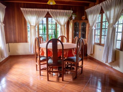 comedor con mesa, sillas y ventanas en Hospedaje Cattleya, en Oxapampa