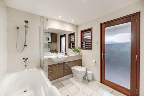 a bathroom with a tub and a toilet and a sink at The Seaglass Villa Private Pool and Sauna in Sunshine Beach