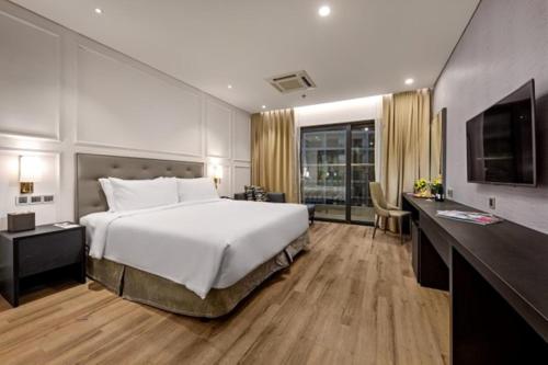 um quarto com uma grande cama branca e uma televisão em Goldenbay Danang 1 Bedroom Apartment em Da Nang
