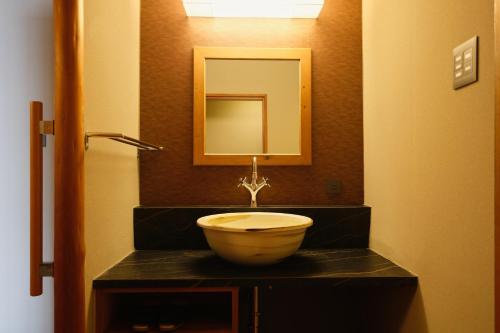 a bathroom with a bowl sink and a mirror at Keishokan Sazanamitei in Fukuyama