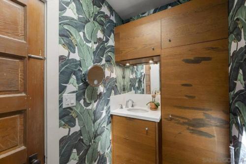 a bathroom with a sink and a leafy wallpaper at Cute Hillcrest cottage in San Diego